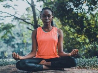 A woman in meditation pose in a forest setting during cultural immersion retreats