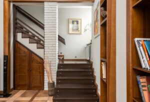 Modern wooden staircase with built-in storage, with a wooden door, showcasing smart staircase storage trends for compact living spaces