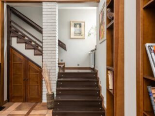 Modern wooden staircase with built-in storage, with a wooden door, showcasing smart staircase storage trends for compact living spaces