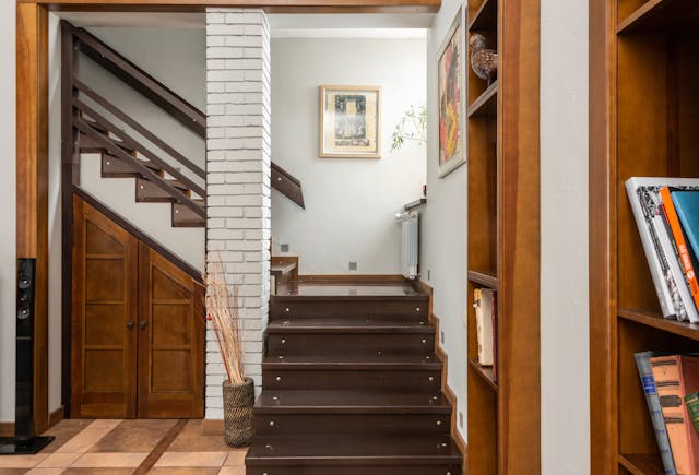 Modern wooden staircase with built-in storage, with a wooden door, showcasing smart staircase storage trends for compact living spaces