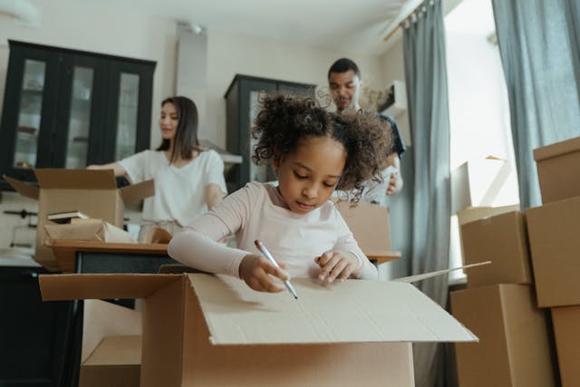 A little girl drawing on a cardboard box