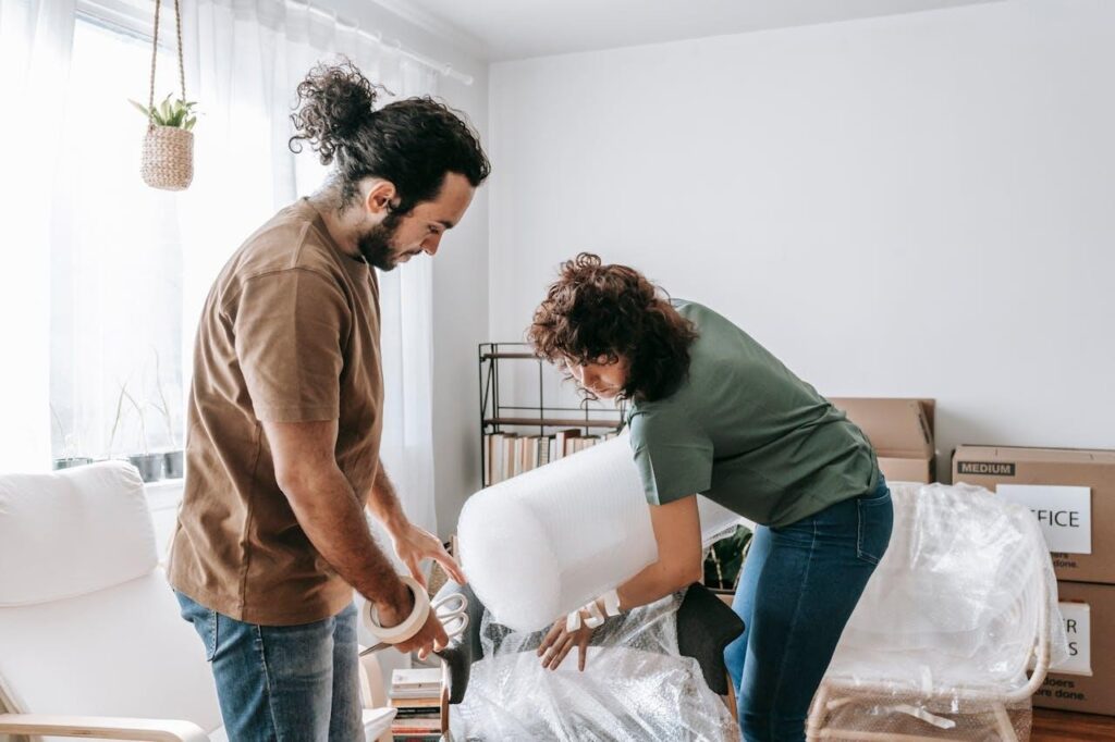 Couple covering a furniture piece with bubble wrap