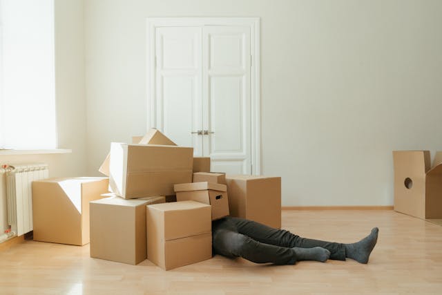 man under many packing boxes