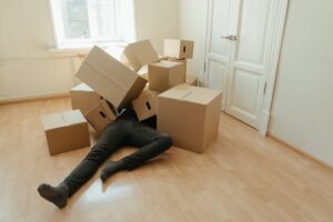 man lying under moving boxes